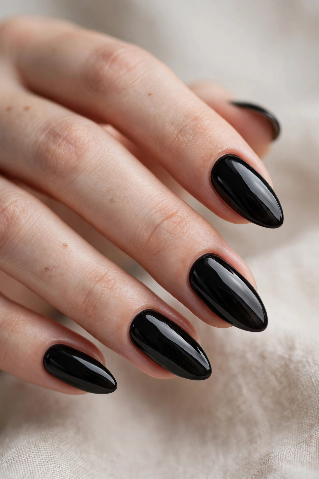 Glossy jet black nail designs on elegant almond shaped nails with mirror shine
